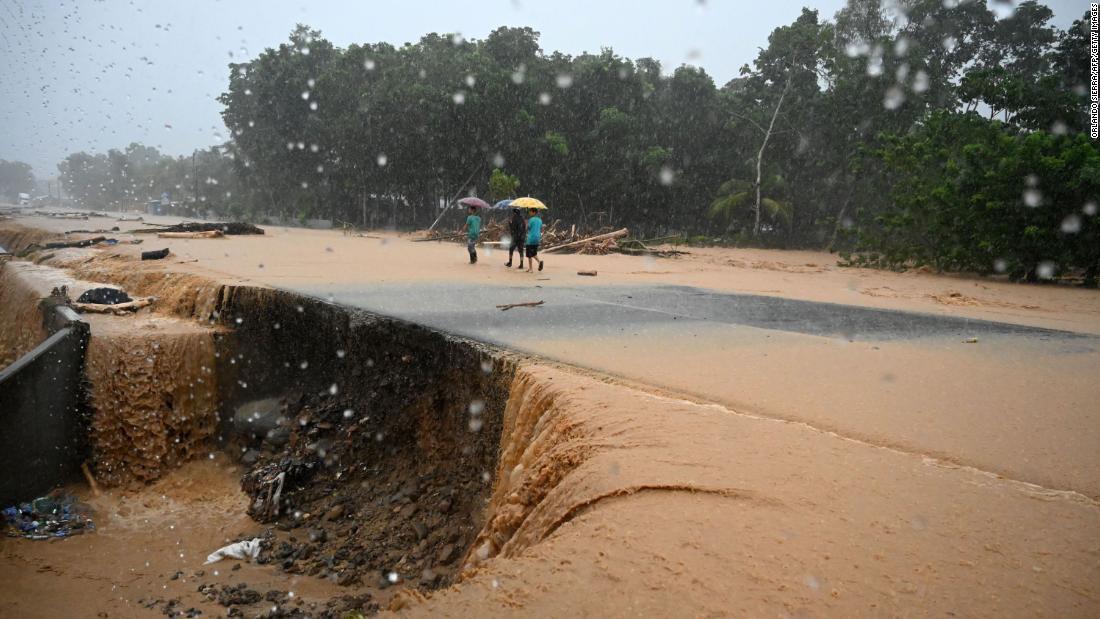 川が氾濫し、冠水した道路をあるく人々＝４日、ホンジュラス/Orlando Sierra/AFP/Getty Images