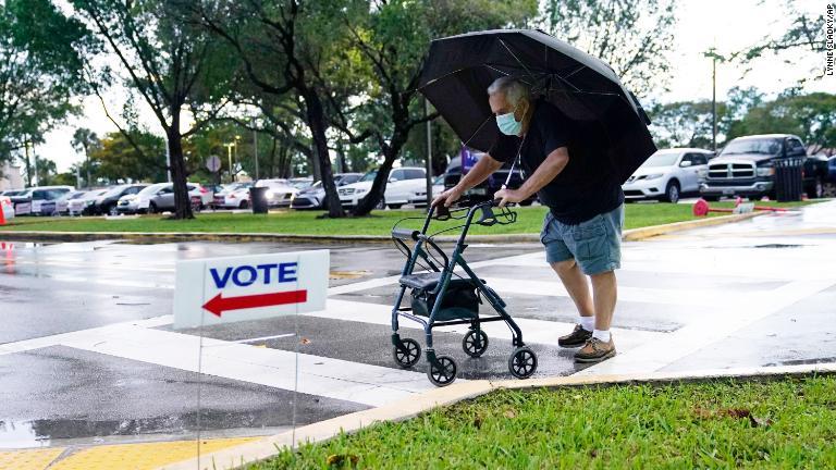 マイアミの期日前投票の会場に雨の降る中徒歩で向かう男性＝１０月１９日/Lynne Sladky/AP
