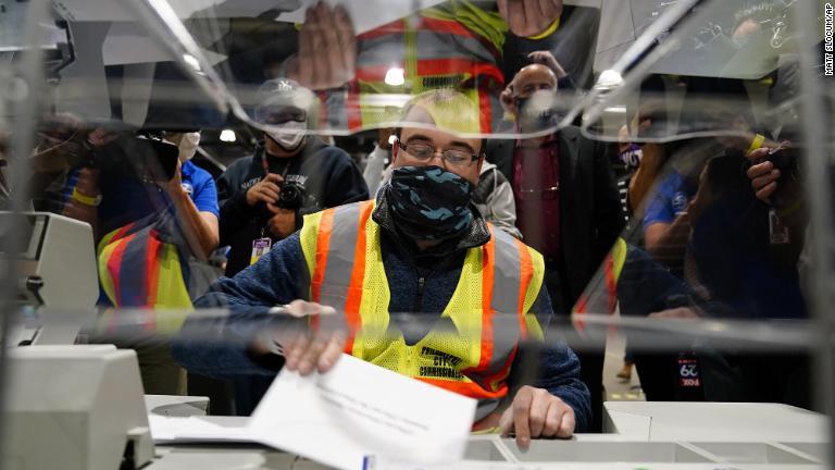 フィラデルフィアのセンターで郵便投票の仕分けと集計を行う機械の仕組みを説明する選管関係者/Matt Slocum/AP