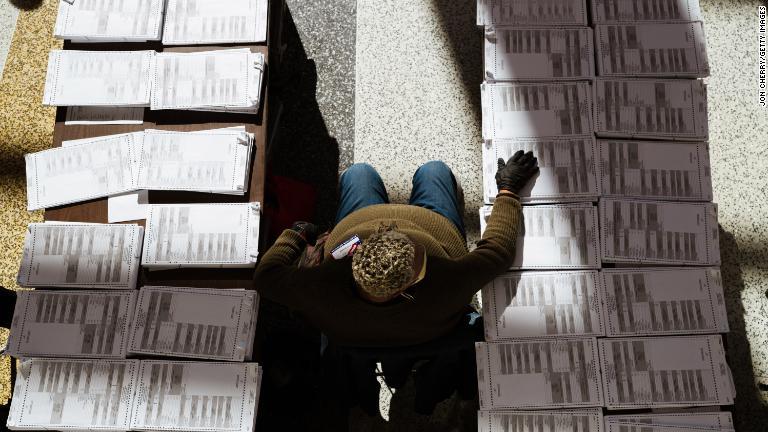 ケンタッキー州ルイビルで未記入の投票用紙の間に座る選管当局者/Jon Cherry/Getty Images
