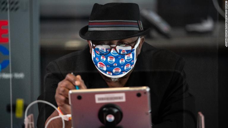 ニューヨーク市ブルックリンの投票者でタブレットを操作する作業員。コロナウイルスの影響でニューヨーク州は期日前投票を認めた＝１０月２６日/Jeenah Moon/Bloomberg/Getty Images