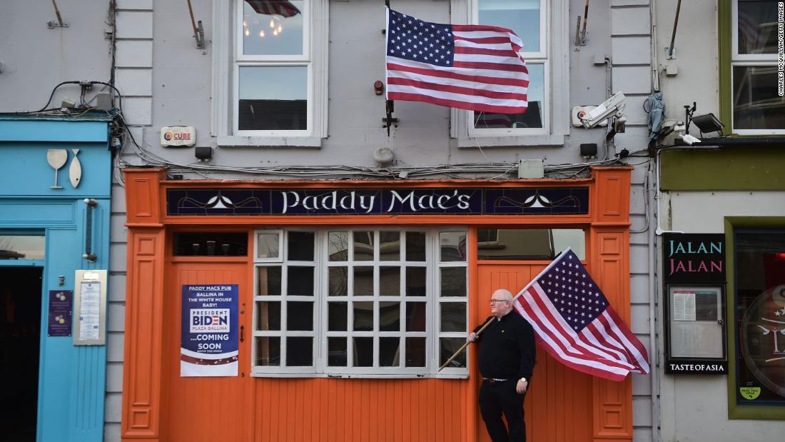 バーの店主が米国旗を持って店の前に立つ様子=7日/Charles McQuillan/Getty Images