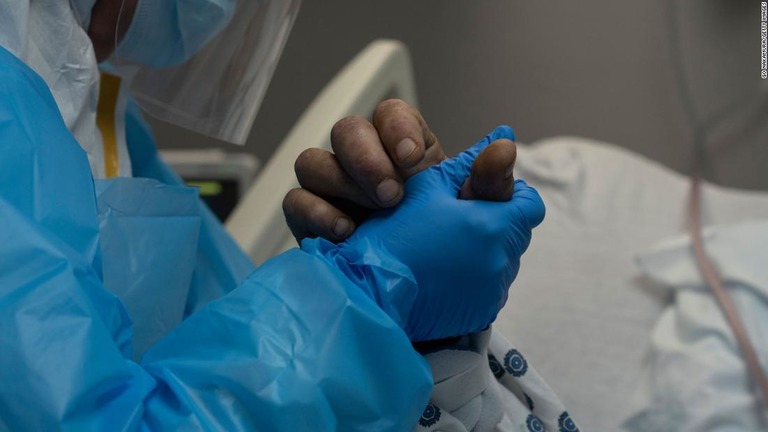 米テキサス州ヒューストンの病院の集中治療室（ＩＣＵ）で患者の手を握る医療関係者＝１１月１０日/Go Nakamura/Getty Images
