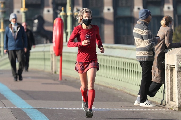 マスクを着用してロンドンのウェストミンスター橋を走る女性/Yui Mok/PA Images/Getty Images