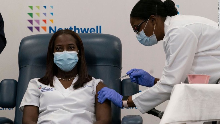 新型コロナワクチンを接種する看護師のサンドラ・リンゼイさん（左）＝１４日/Mark Lennihan/Pool/Getty Images