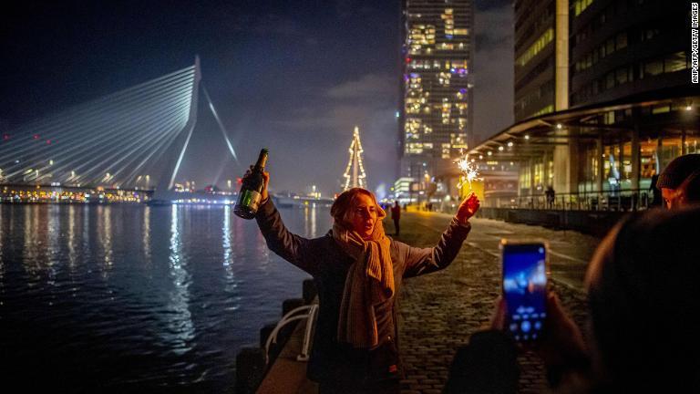 オランダ第2の都市ロッテルダムのエラスムス橋でお酒を片手に新年を祝う人/ANP/AFP/Getty Images