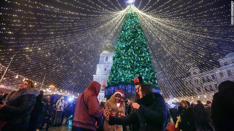 ウクライナ首都キエフでクリスマスツリーの光の装飾の下で祝う人々/Efrem Lukatsky/AP
