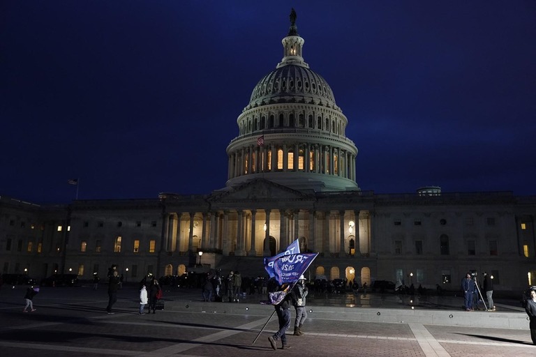 連邦議会議事堂前で旗を持つトランプ氏支持者/Jacquelyn Martin/AP