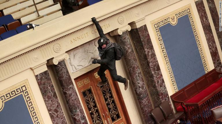 上院議場のバルコニーに手でぶら下がる暴徒/Win McNamee/Getty Images