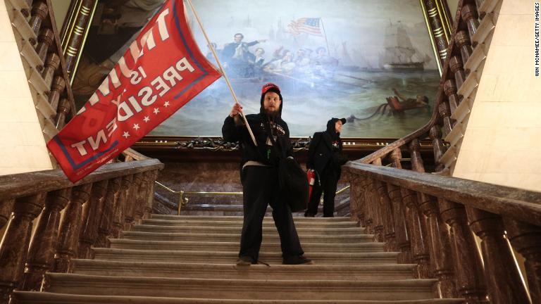暴徒が連邦議会議事堂の上院議場付近でトランプ氏支持の旗を持つ/Win McNamee/Getty Images