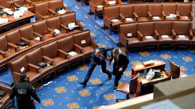 暴徒が下院議場に入ろうとする中、下院メンバーは避難しようと走る/Drew Angerer/Getty Images