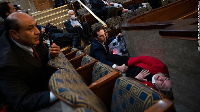 下院の議場で身を隠す下院議員のジェーソン・クロー氏（コロラド州）と同氏がいたわるスーザン・ワイルド氏（ペンシルベニア州）/Tom Williams/CQ-Roll Call, Inc via Getty Images