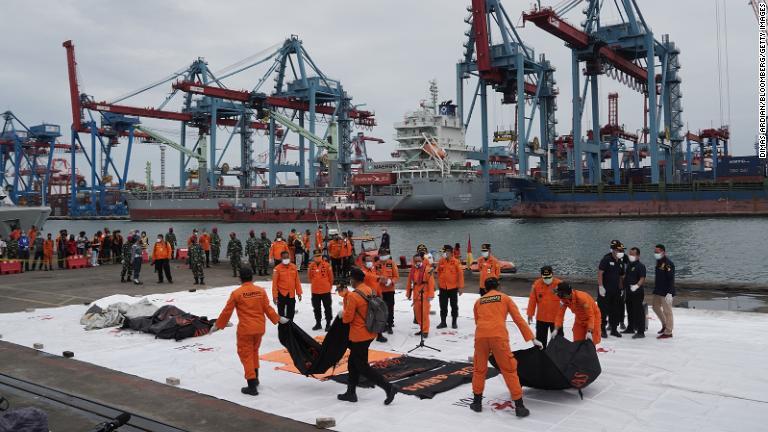 墜落した現場海域から回収した遺体収容の袋を運ぶ捜索救助チーム＝１０日/Dimas Ardian/Bloomberg/Getty Images