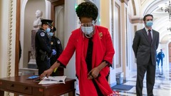 テキサス州選出の民主党下院議員、シーラ・ジャクソン・リー氏が議場に入る前に自分の書類を集めて手に取る様子。先週の議事堂襲撃の後、議員は金属探知機を通過する必要がある＝１３日