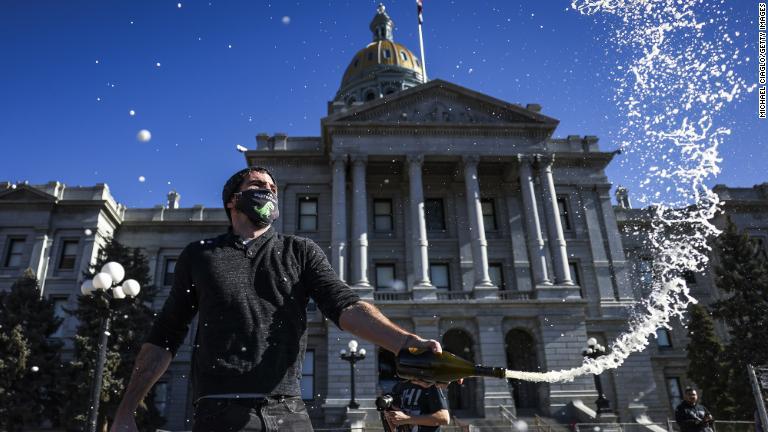 コロラド州デンバーの州議会議事堂前でシャンパンをあけるキース・ホドソンさん/Michael Ciaglo/Getty Images