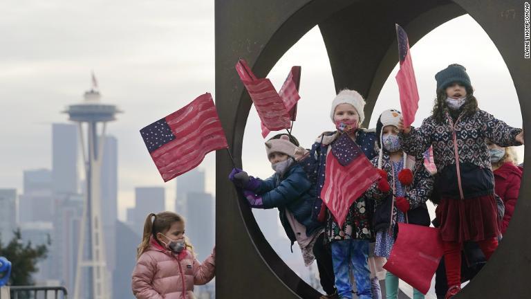 シアトルの子どものワークショップのメンバーは就任式を祝うために作った旗を持ち彫刻の中でポーズ/Elaine Thompson/AP