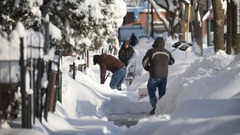 道路の雪かきをする人たち＝１６日、イリノイ州シカゴ