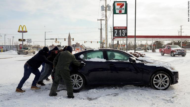 はまった車を押す人たち＝１５日、オクラホマ州オクラホマシティー/Nick Oxford/Reuters