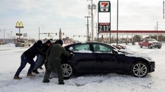 はまった車を押す人たち＝１５日、オクラホマ州オクラホマシティー