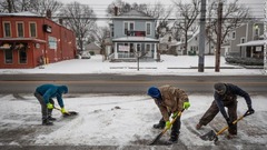 店の前の雪かきをする人たち＝１５日、ケンタッキー州ルイビル