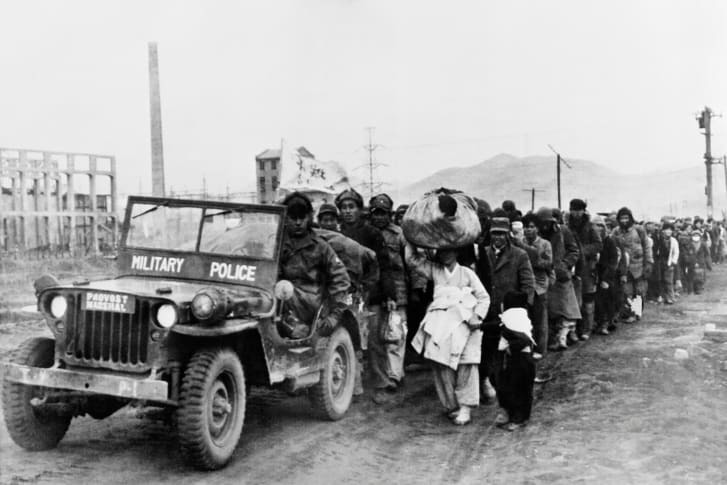 １９５０年１２月２６日に公開された写真。軍警察に護衛され、朝鮮の市民が韓国へと逃れていく。朝鮮戦争の最中に撮影されたもの/AFP/Getty Images