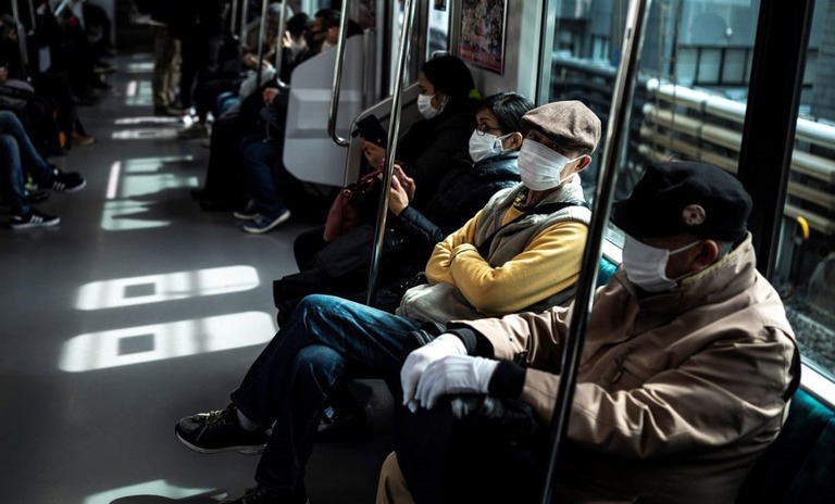 マスクを着用して東京都内を走る電車を利用する人たち/Charly Triballeau/AFP/Getty Images