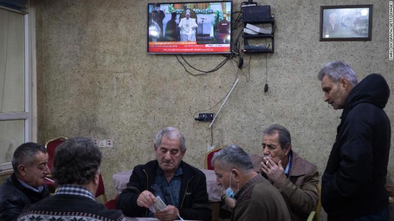 アルビルの飲食店でカード遊びをする人々。背後のテレビがフランシスコ教皇のイラク訪問を伝えている/Chris McGrath/Getty Images