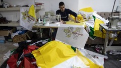 アルビルの作業所でバチカンの旗の縫製を行う男性
