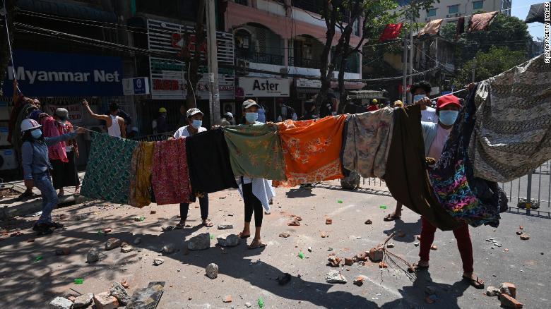 伝統的な巻きスカート「ロンジ—」を広げて道路をふさぐヤンゴンの抗議デモ参加者ら/STR/AFP/Getty Images