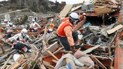 がれきの中から生存者を探す救助隊員。宮城県南三陸町