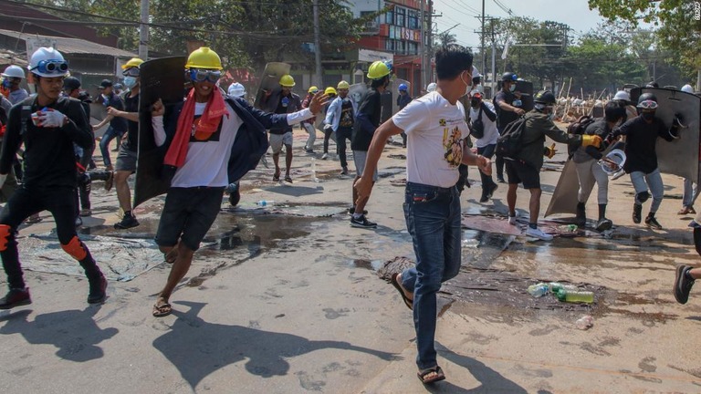 最大都市ヤンゴンで警官隊の発射するゴム弾を避けようと駆け出す抗議デモ参加者ら/STR/AP