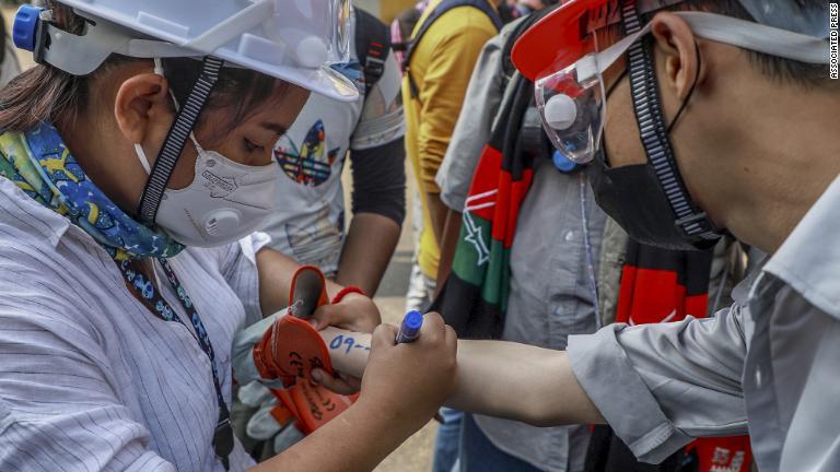 デモ参加者が別の参加者の腕に緊急時の重要情報を書き記す＝ヤンゴン/Associated Press