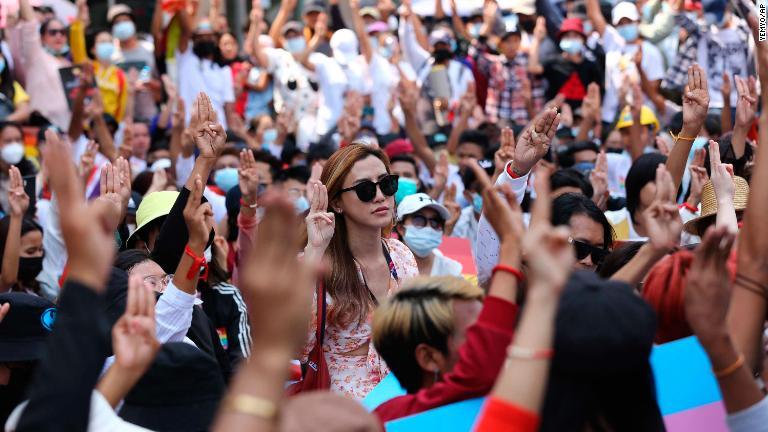 人差し指と中指、薬指を並べて腕を上げるデモ参加者＝２月１９日、ヤンゴン/YeMyo/AP