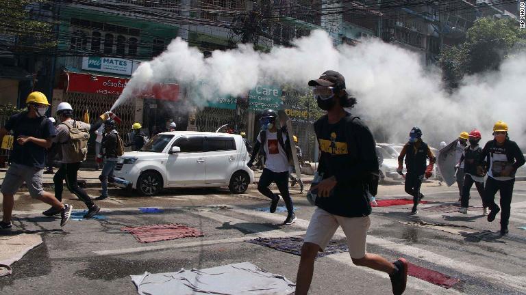 催涙ガスの発射に消火器を噴射して対抗するデモ参加者＝８日、ヤンゴン/AP Photo