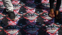 ミンアウンフライン国軍司令官の写真の上を歩くデモ参加者＝５日、ヤンゴン