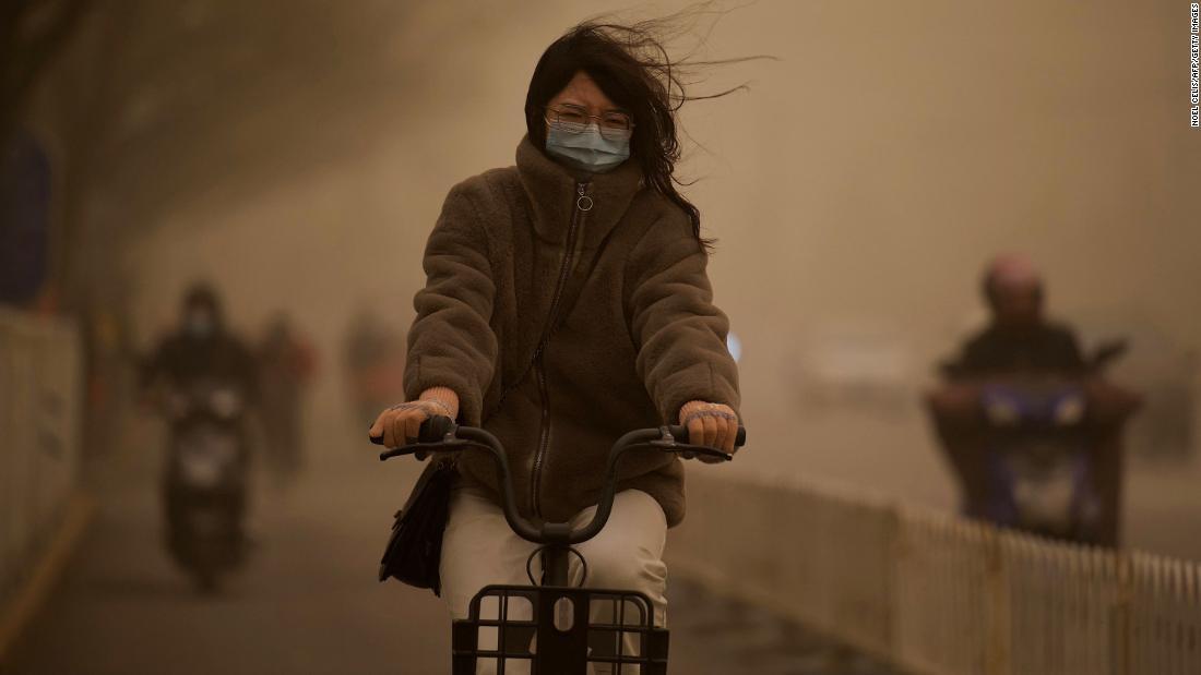 黄砂の中で自転車をこぐ女性＝１５日/Noel Celis/AFP/Getty Images