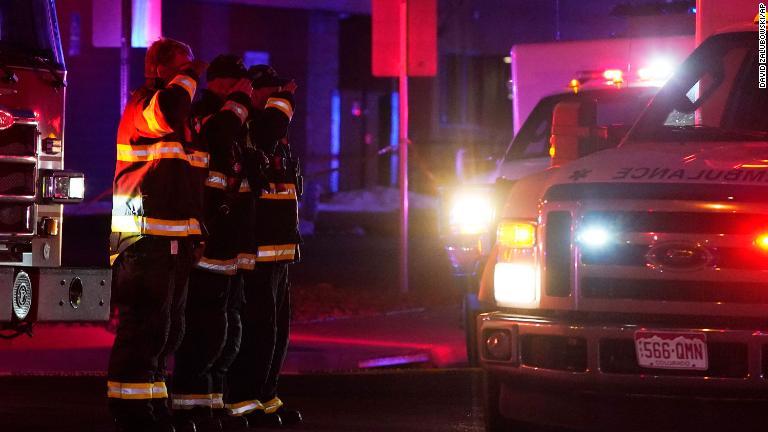 銃撃現場を去る救急車に敬礼する消防士/David Zalubowski/AP