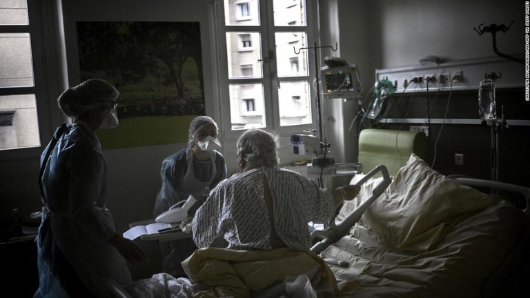 パリの病院で新型コロナ感染者がベッドに座るのを助ける看護師＝３月１８日/CHRISTOPHE ARCHAMBAULT/AFP/AFP via Getty Images