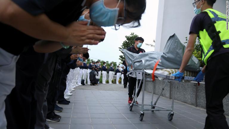 搬送される遺体に手を合わせる仏教系慈善団体のメンバー/Annabelle Chih/Reuters