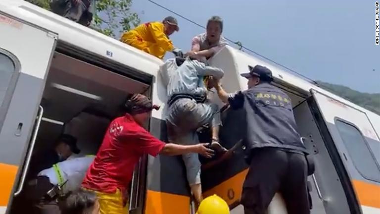 救助隊員の助けを借りて列車から脱出する人/hsnews.com.tw via AP
