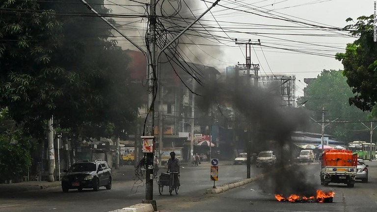 燃えるバリケードの横を通過する車両＝３日、ミャンマー・ヤンゴン/STR/AFP/Getty Images