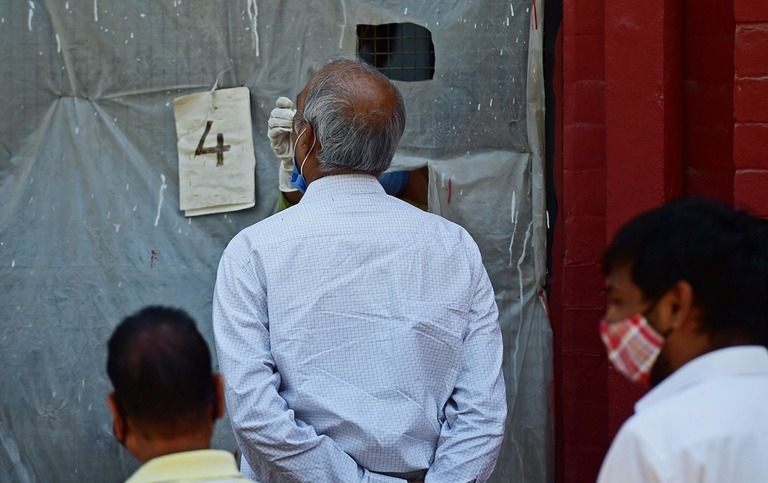 インド北部アラハバードで保健当局者から新型コロナ検査用のサンプルを採取される男性/Sanjay Kanojia/AFP/Getty Images