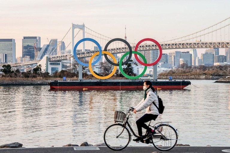 五輪のシンボルの横を自転車で走る人＝１月２５日/Viola Kam/SOPA Images/LightRocket/Getty Images