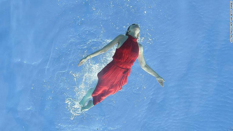 正式オープンを前に行われた宣伝撮影会では、赤いドレス姿のモデルが泳ぐ姿を披露した/JUSTIN TALLIS/AFP via Getty Images