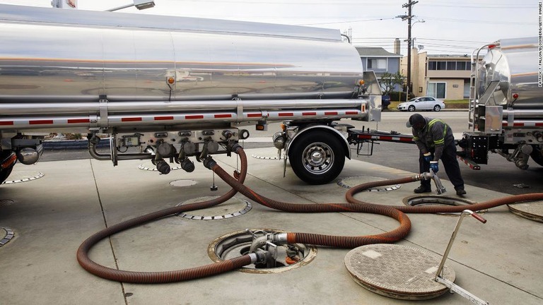カリフォルニア州のスタンドでガソリン注入用のホースの処理に従事する作業員/Patrick T. Fallon/Bloomberg/Getty Images