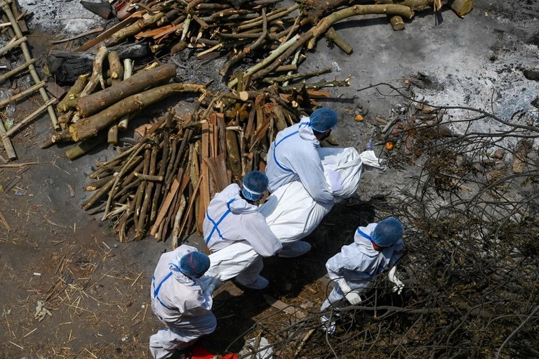個人用防護具（ＰＰＥ）を着用して新型コロナウイルスの犠牲者を運ぶ遺族と救急隊員＝２７日、インド・ニューデリー/Prakash Singh/AFP/Getty Images