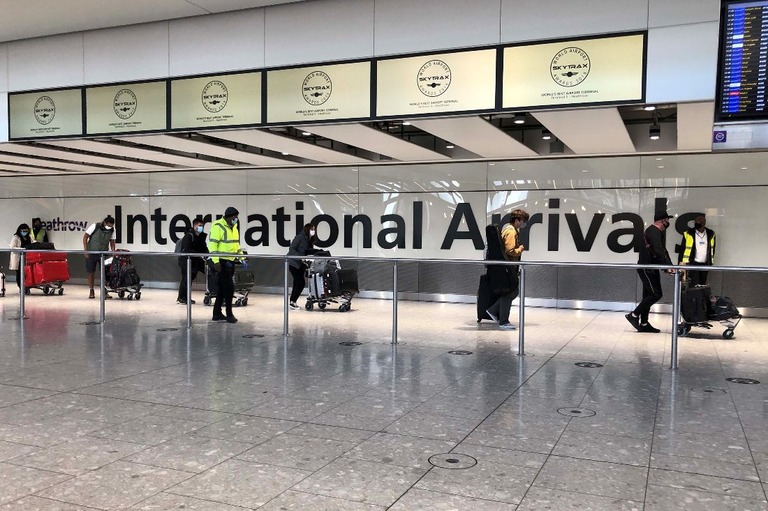 隔離用ホテルへ向かうバスに乗るため空港内を移動する人たち＝２３日、英ロンドンのヒースロー空港/Leon Neal/Getty Images