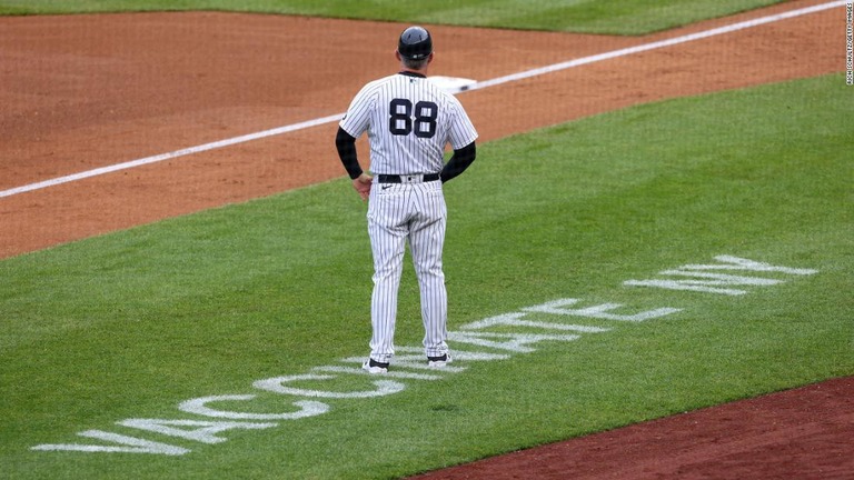 ワクチン接種を呼びかける文字のある芝に立つニューヨーク・ヤンキースの三塁コーチ＝８日、米ニューヨーク市のヤンキースタジアム/Rich Schultz/Getty Images