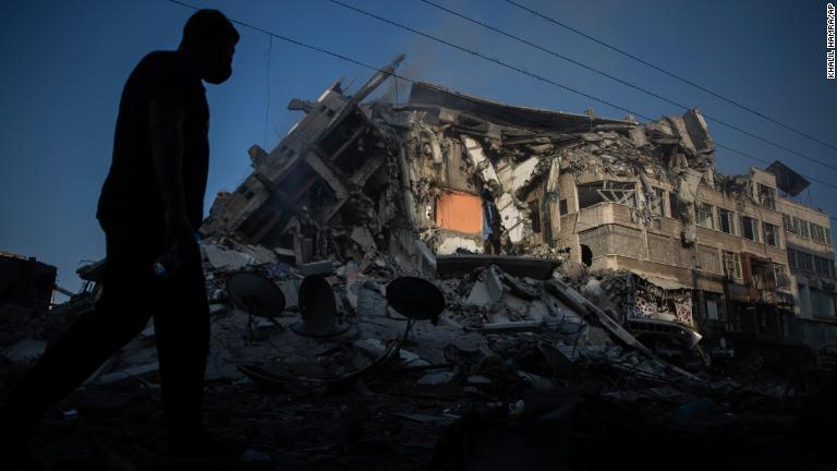 破壊された家屋の横を歩くパレスチナ人＝１３日/Khalil Hamra/AP