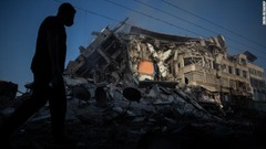 破壊された家屋の横を歩くパレスチナ人＝１３日